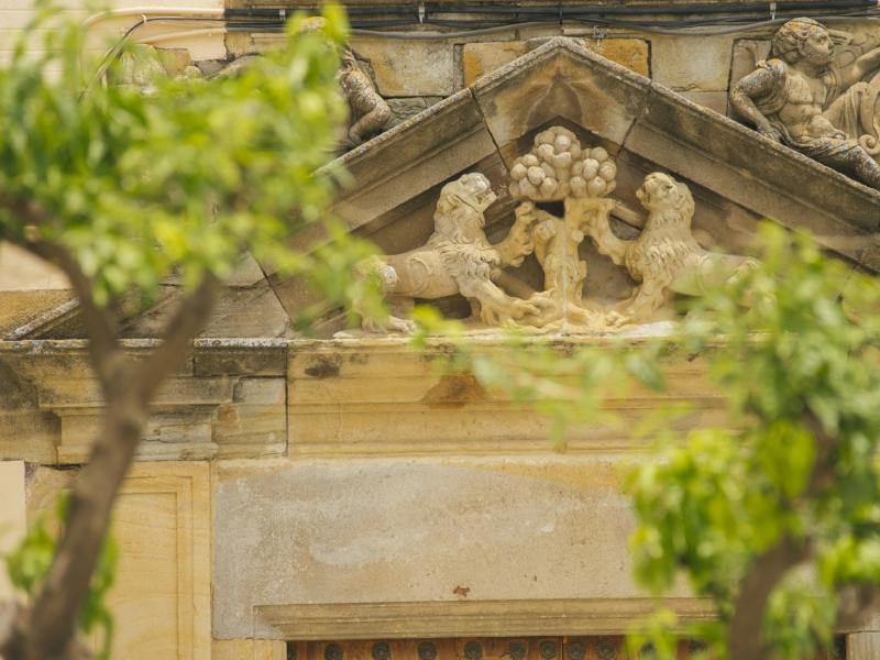 Vista parcial de la entrada de la casa palacio, dos leones y un naranjo en piedra