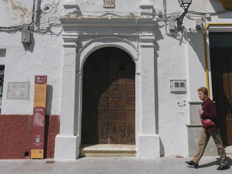 Mujer paseando frente a la entrada de la Capilla de la Santísima Trinidad