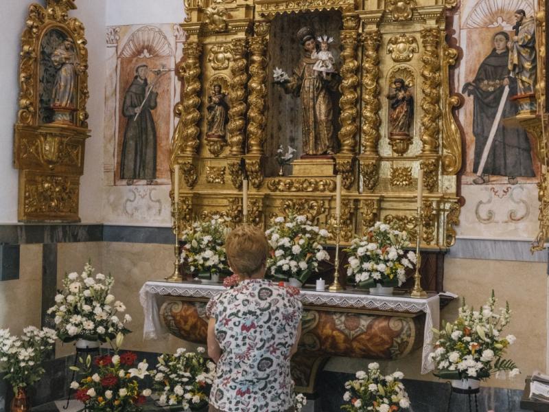 Señora rezando en una capilla adornada con flores