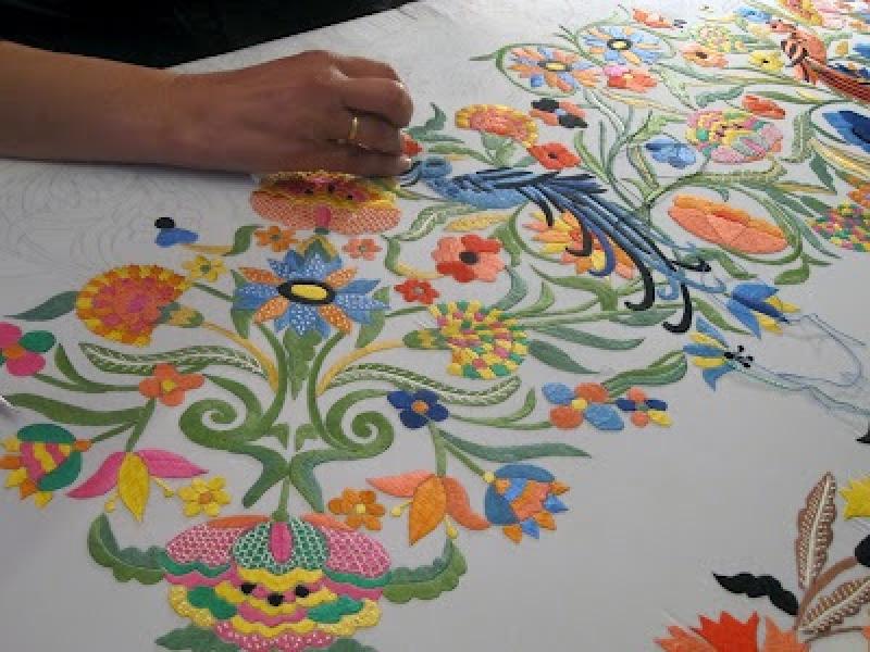 Artesana haciendo un trabajo de bordado de flores de diversos colores
