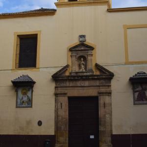 Imagen de la fachada de la iglesia de san nicolás de bari donde se ve la puerta de entrada y dos azulejos de imágenes religiosas a ambos lados de la misma